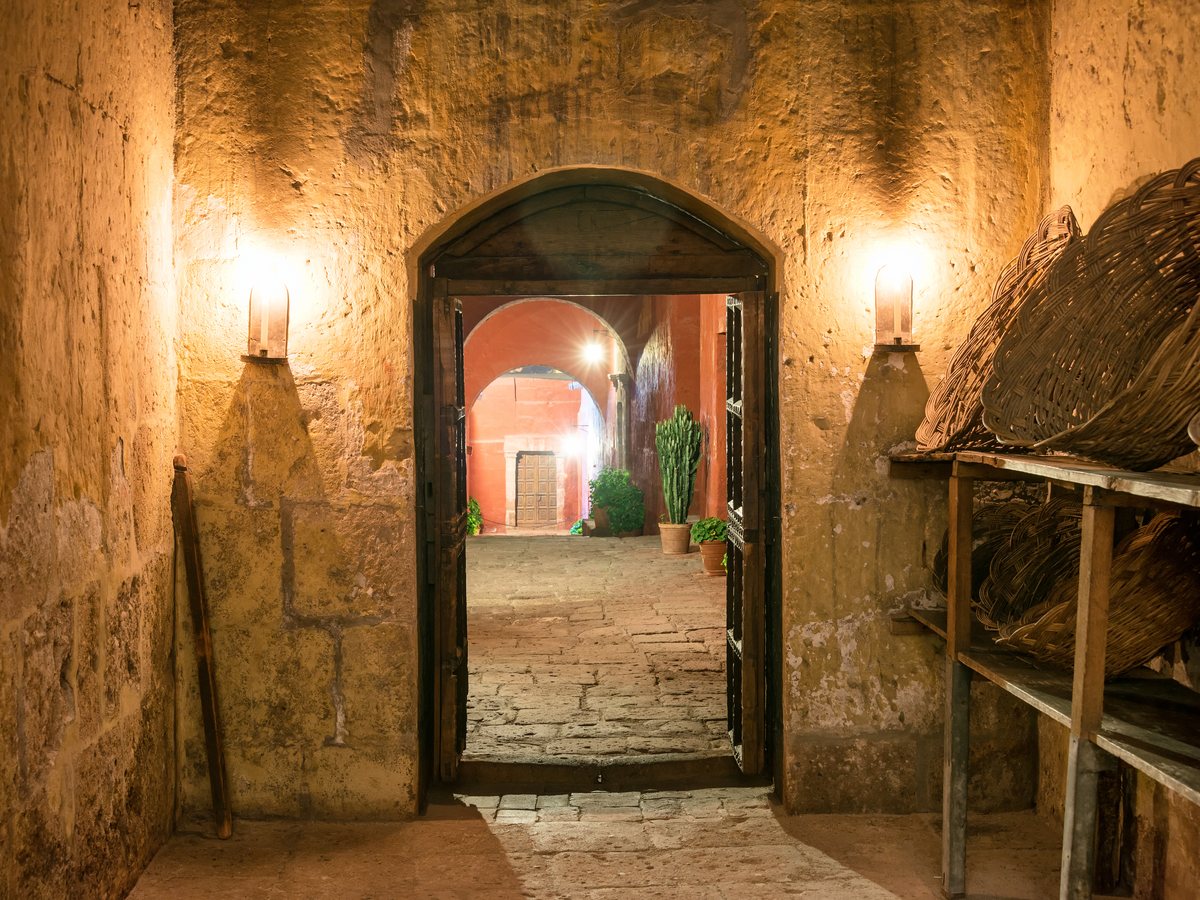Pasillo de piedra iluminado con faroles en una casona histórica