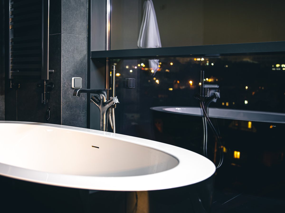 Baño de hotel urbano con tina frente a la ciudad de noche